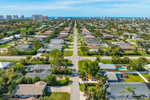 An aerial view of a neighborhood in Naples, FL, shows the Gulf of Mexico in the distance.