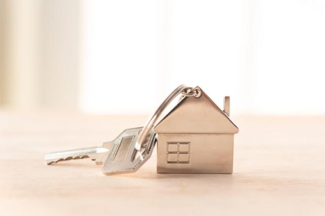 A close-up shot of a silver key attached to a house keychain.