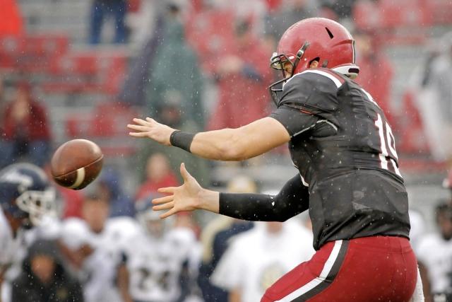 A football player in a black and red uniform catching a football.