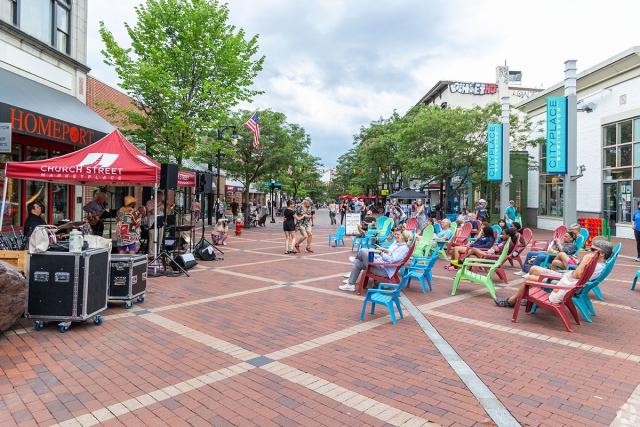 People sitting and dancing while listening to live music on a pedestrian-only street.