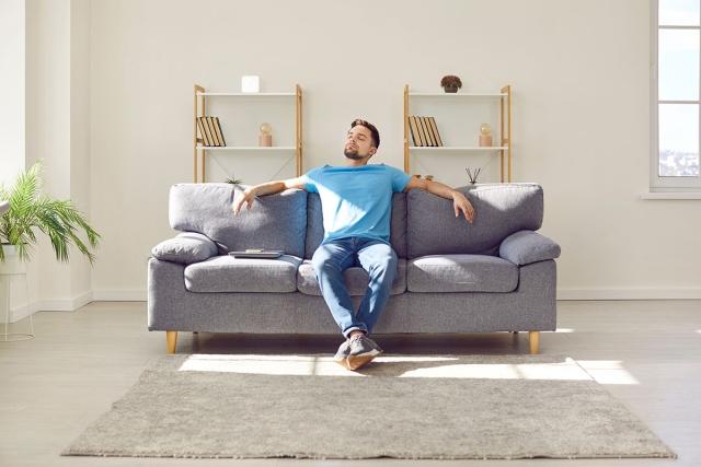 A solo renter sitting on the couch by himself.