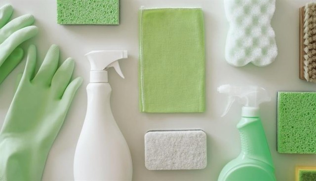 A variety of cleaning supplies in shades of green and white.
