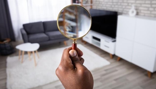 Person holding up a magnifying glass to search an apartment living room