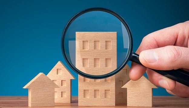 Magnifying glass inspecting wooden building blocks in the shape of houses