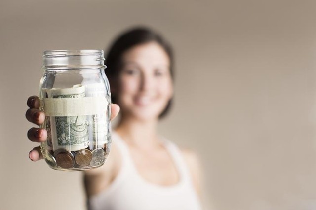 Woman holds jar filled with money