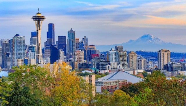 Aerial view of Seattle, WA shows the Space Needle and mountains.