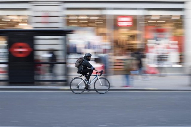 A bicyclist speeds past businesses