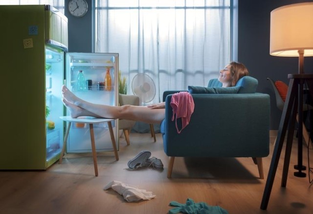 a woman cooling herself in front of an open fridge