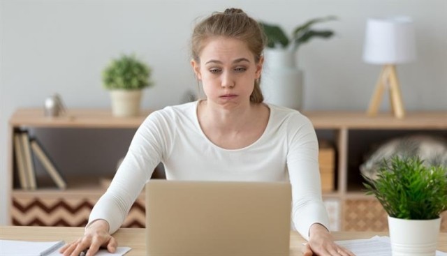 Woman on the verge of tears sits in front of her laptop. 