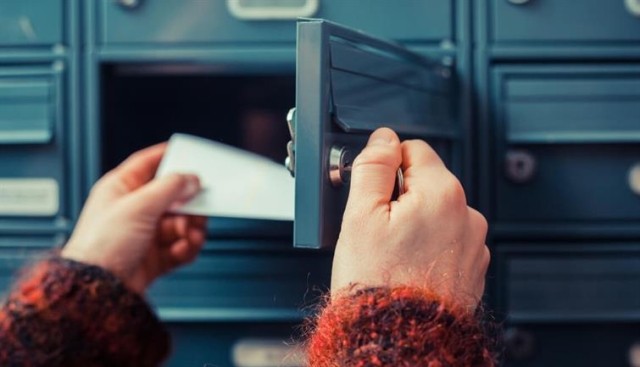 Person reaching into an apartment mailbox.