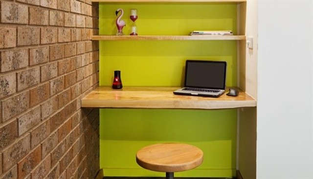 A small nook serving as a home office with shelves and a stool.