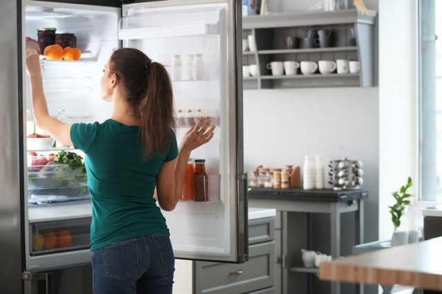 Woman searching through fridge