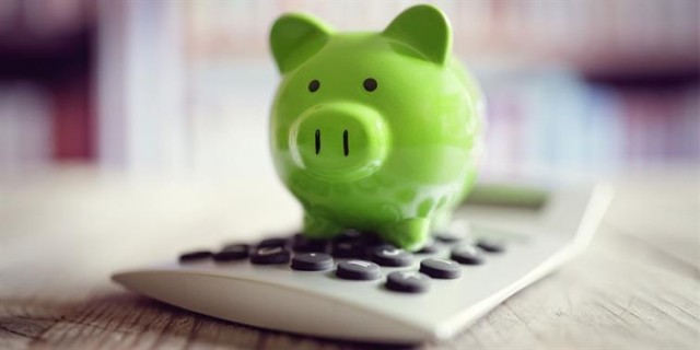 A green porcelain piggy bank set atop a calculator