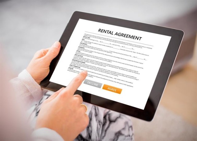 A person signing a rental agreement on a tablet.