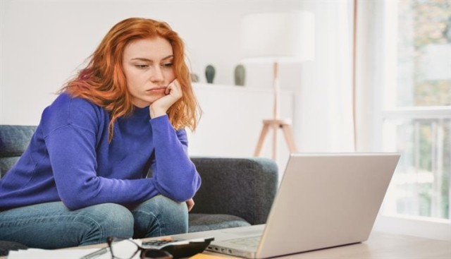 Depressed woman sits in front of a laptop.