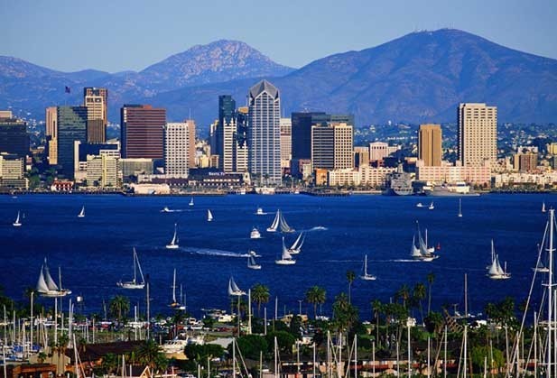 San Diego skyline framed by mountains in the background and boats on the water.
