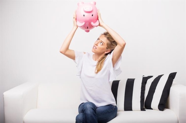 woman looking for money in piggy bank