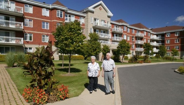 An older couple walking outside an apartment community.