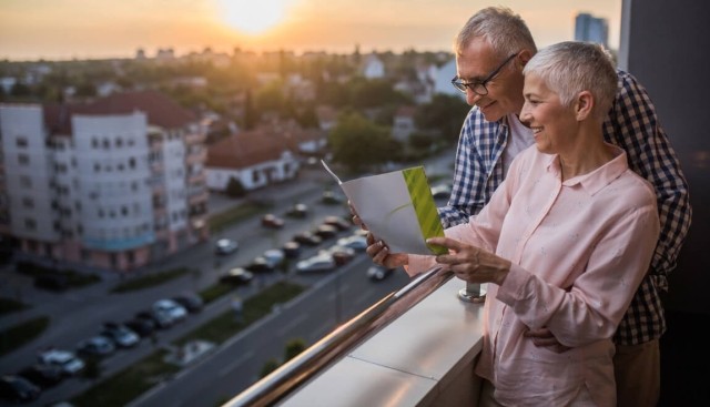 An older couple standing on a balcony at sunset.