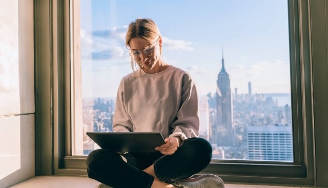 Woman on laptop computer with city skyline behind her.