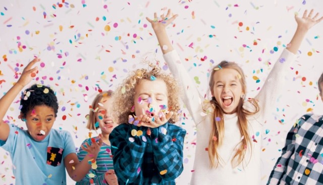 A picture of children throwing confetti in the air.