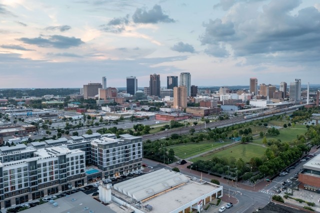 High-rise buildings tower over Birmingham, Alabama, in an aerial view of the city at sunset.