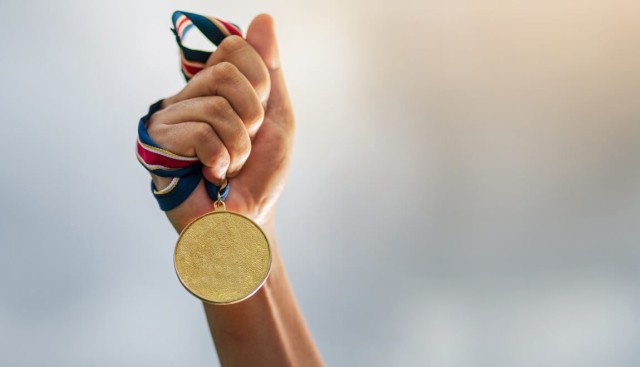 Gold medalist holds up their award. 