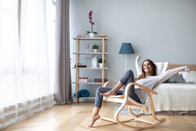 An excited young woman sits in an apartment bedroom.