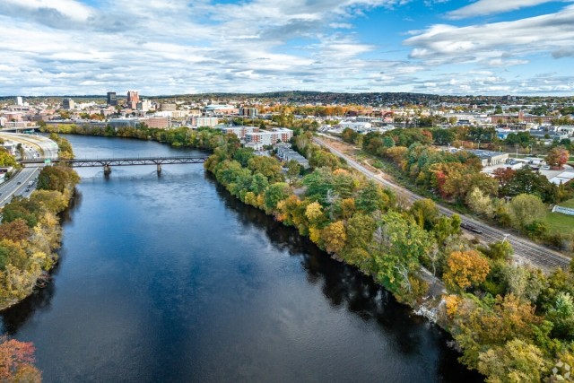 An aerial view of the Merrimack River shows Downtown Manchester in the distance.