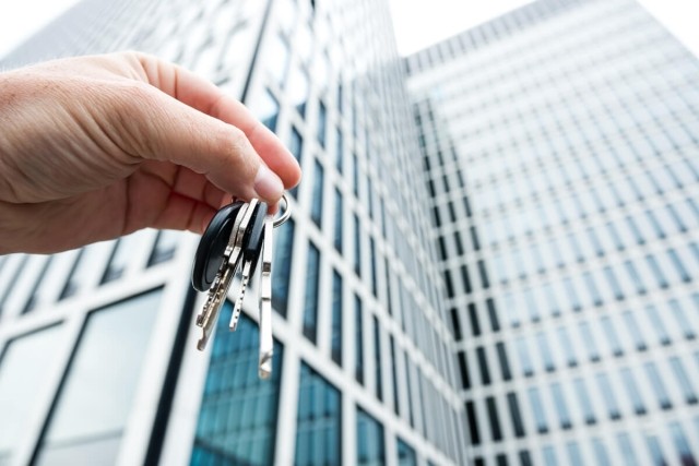 Tenant holding keys in front of apartment building.