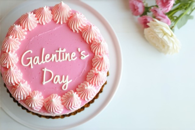 A pink cake reads "Galentine's Day" in white frosting.