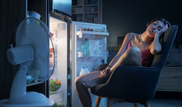 Renter trying to get cool in hot apartment by sitting in front of the refrigerator.