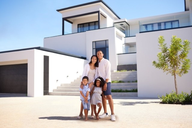 Millionaire family posing in front of a large home