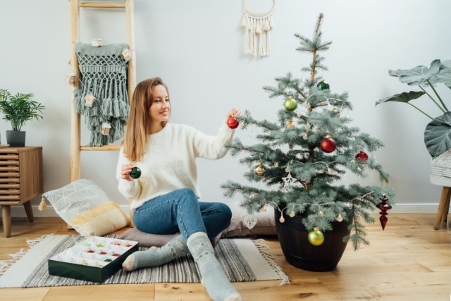 Woman decorates apartment Christmas tree.
