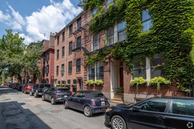 Line of parked cars out in front of brick apartment buildings in Boston.