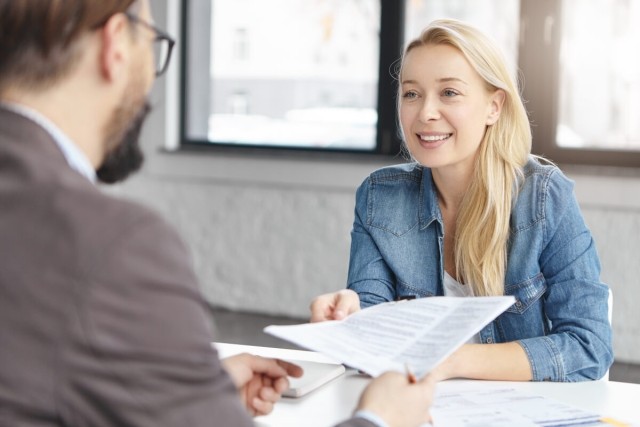 Lady handing paper to landlord while smiling and discussing.