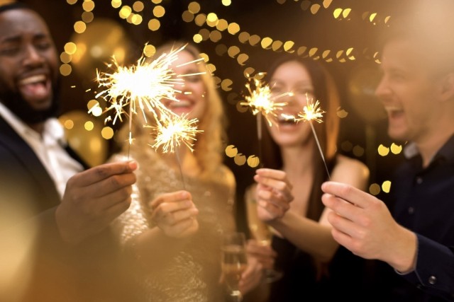 Four friends hold sparklers on New Year's Eve.