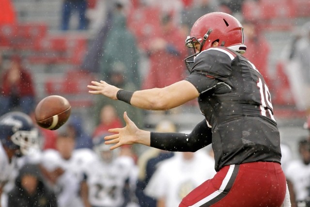 A football player in a black and red uniform catching a football.