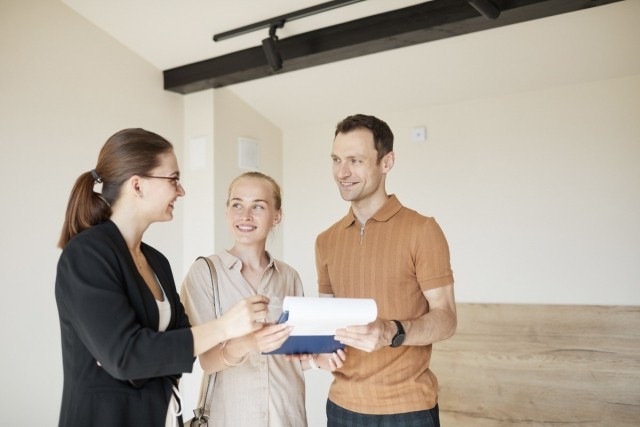 A young couple talks with a property manager while touring an apartment.