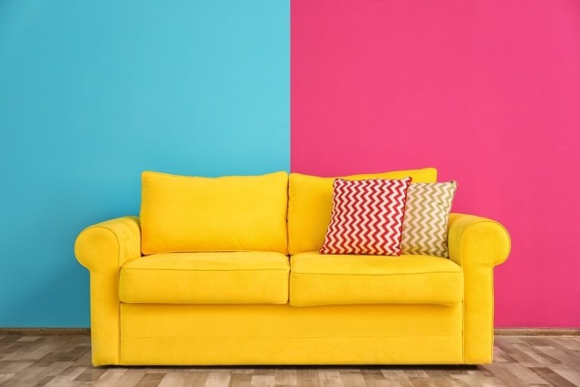 A bright yellow sofa set against a 2-tone wall of vivid colors