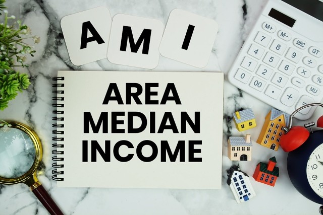 Area Median Income written in a notebook with a calculator and model houses surrounding it.
