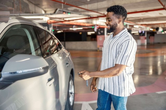 A man inside a parking garage unlocks the door to his car.