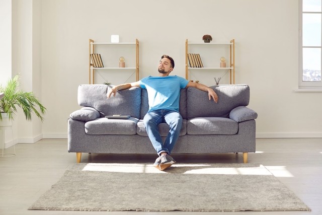 A solo renter sitting on the couch by himself.