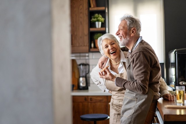 Senior couple laughing in their kitchen.
